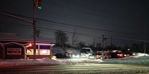 A crowded Chinese food restaurant storefront with a full parking lot, on a snowy street